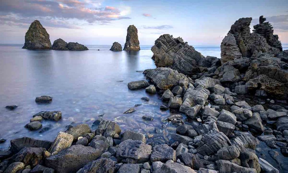 Faraglione di Mezzo e Faraglione Piccolo, Isole Ciclopiche, Aci Trezza, Sicilia, Italia. Queste erano le grandi pietre lanciate contro Odisseo dal mostro Ciclope.